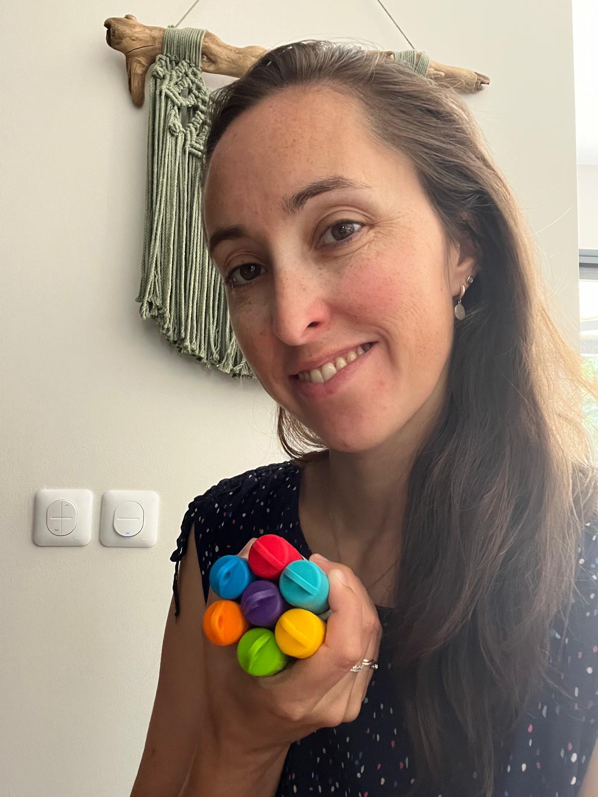 Lucie Gilbert, souriante, tient les 7 roll-on colorés du Kit Enfant