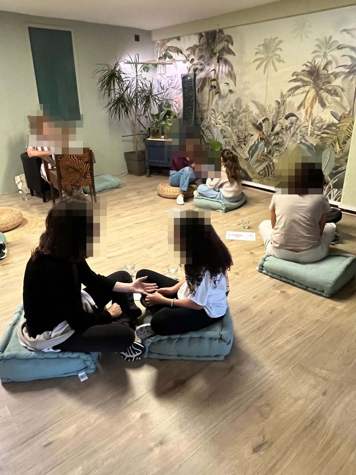 Des duos parent-enfant assis sur des coussins au cabinet, pendant l’atelier de réflexologie de la deuxième matinée