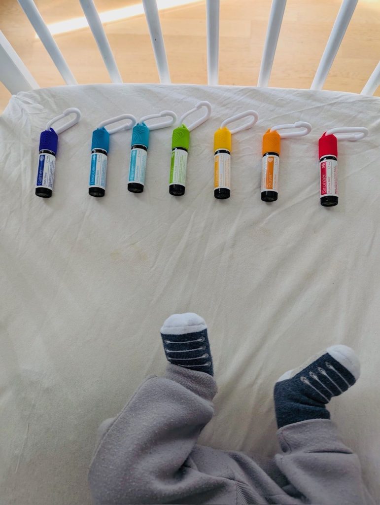 Les roll-on du Kit Enfant alignés au bord d'un lit de bébé, avec ses petits pieds en chaussons