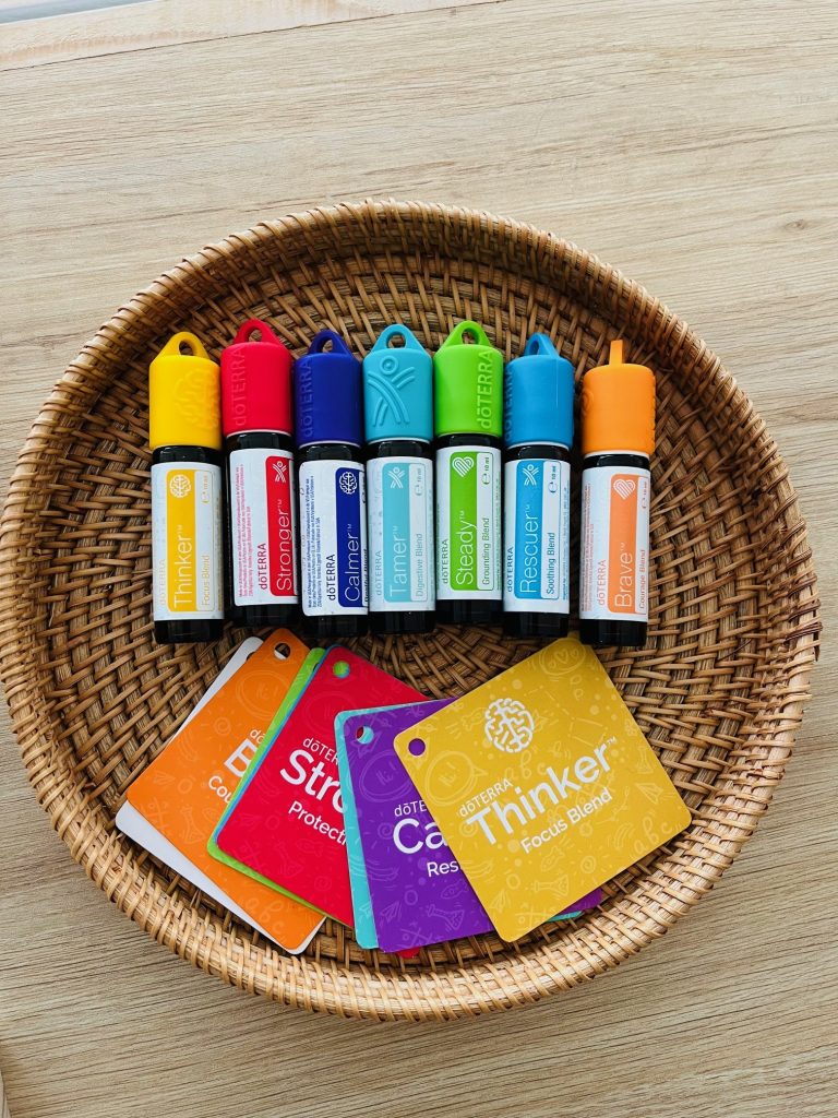 Des roll-on colorés doTERRA dans une corbeille en osier, avec leurs cartes
