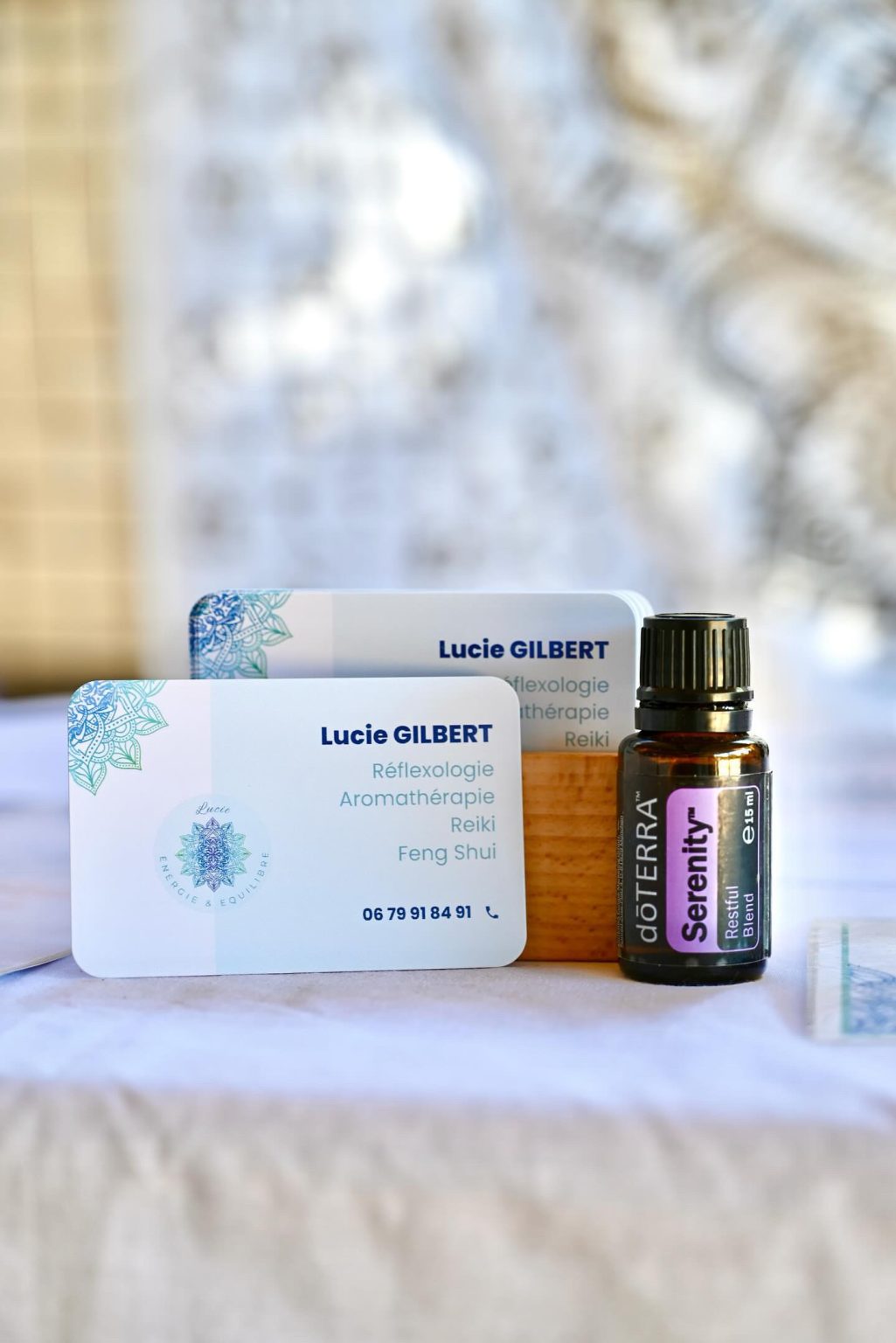 Les cartes de visite de Lucie à côté d'un flacon d'huile essentielle Serenity